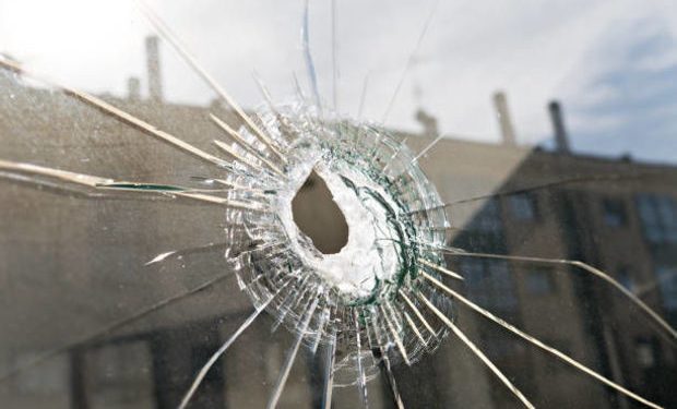 Broken glass with hole and building reflected in the window